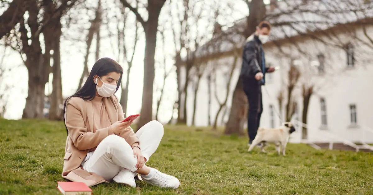 Woman in mask using phone outdoors, man walking dog in autumn park, pet safety concept