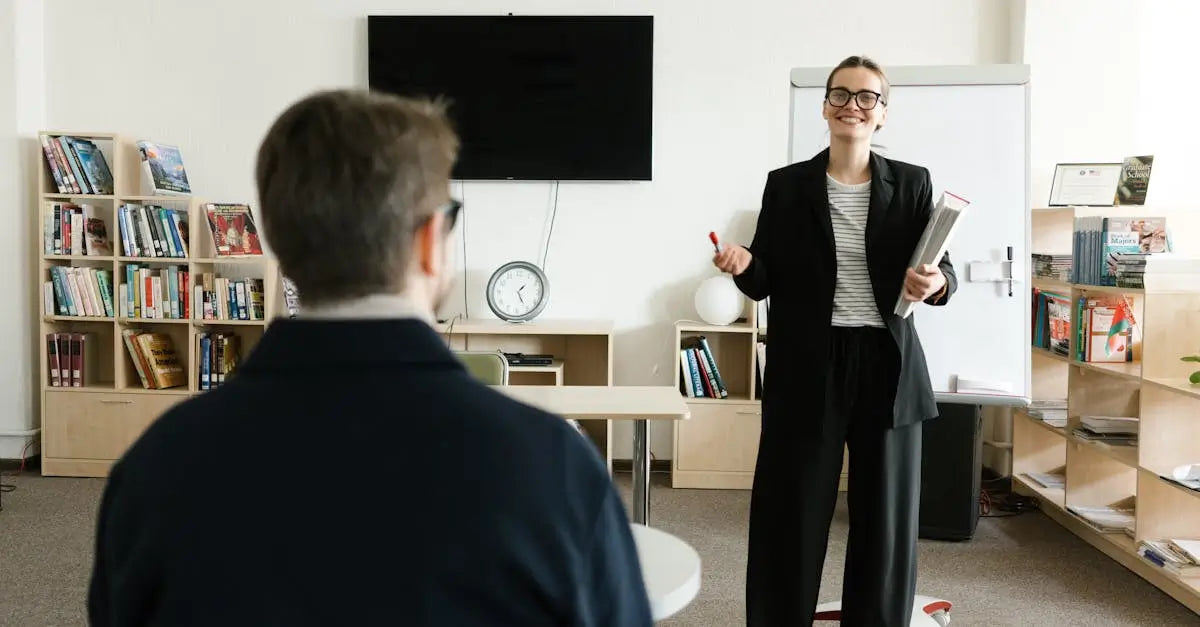 Smiling woman teaching man in classroom with bookshelves and whiteboard in background